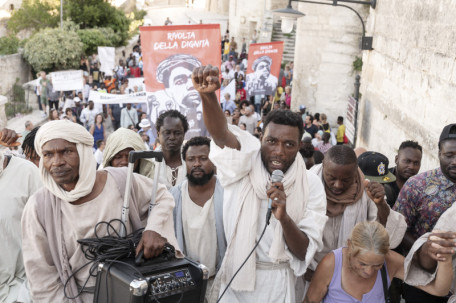 Matera, Italy. The demonstration "La Rivolta della Dignita" at Matera. In the center is Yvan Sagnet, human rights activist, who also plays Jesus in the Milo Rau movie. About the film project: In Matera, in southern Italy, where the great Jesus films from Pasolini to Gibson were shot, the director Milo Rau is staging a modern Passion of the Christ: “The New Gospel“. What would Jesus preach today? Who would his disciples be? Led by political activist Yvan Sagnet, a new Jesus movement is fighting for the rights of migrants who came to Europe across the Mediterranean to be enslaved on the tomato fields in southern Italy and to live in ghettos under inhumane conditions. Rau and his team return to the origins of the gospel and stage it as a passion play of an entire civilization. An authentically political as well as cinematic “New Gospel” emerges for the 21st century. A manifesto of solidarity with the poorest, a revolt for a more just, humane world.